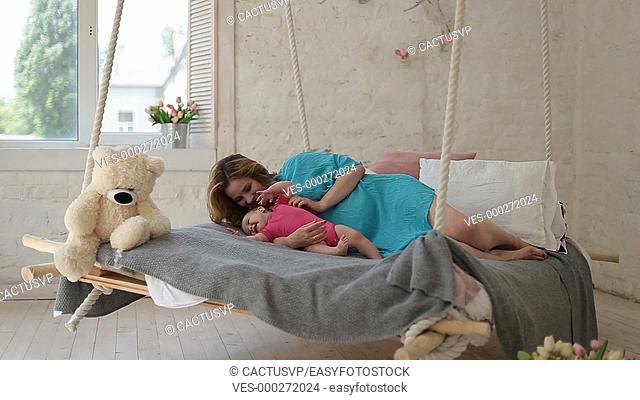 Young mother playing with baby daughter in bed
