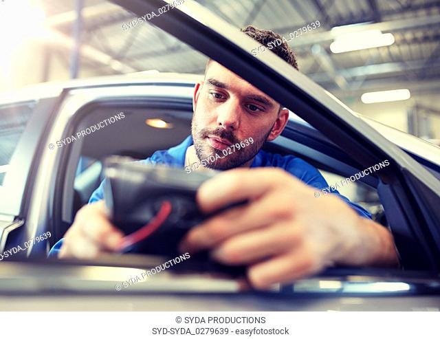 mechanic man with diagnostic scanner at car shop