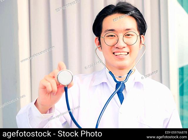 Portrait of Happy Asian young doctor handsome man smiling in uniform holding and show stethoscope, Healthcare medicine concept