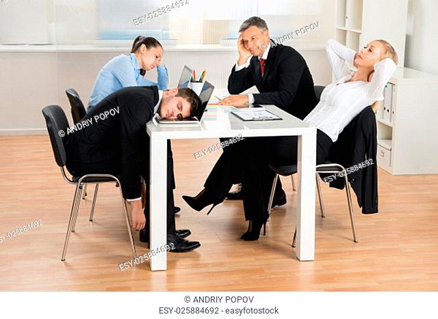 Businesspeople Getting Bored While Sitting At Desk In Office