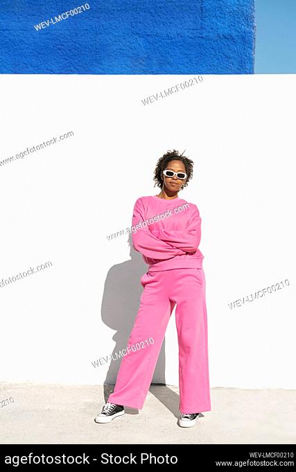 Confident woman wearing sunglasses standing in front of wall