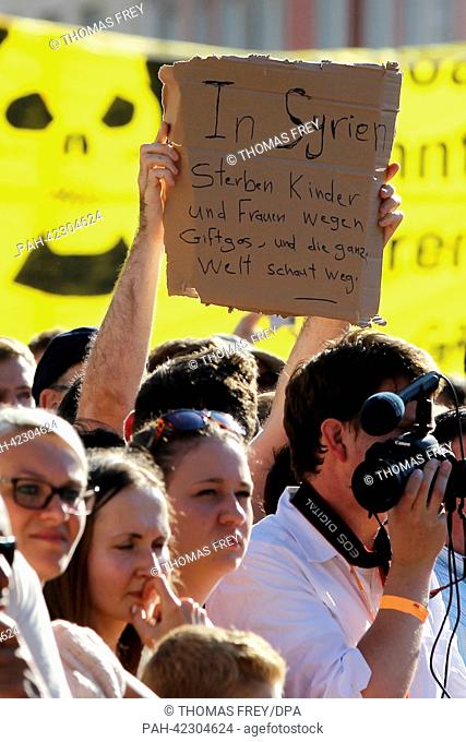 A person holds up a poster with the lettering 'Children and women die in Syria due to toxic gas and the whole world looks the other way' during a speech of...