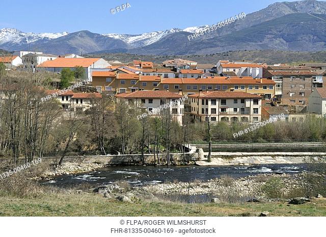 View of river, town and snow-capped mountains in distance, El Barco, Gredos Mountains, Castilla y Leon, Spain, april