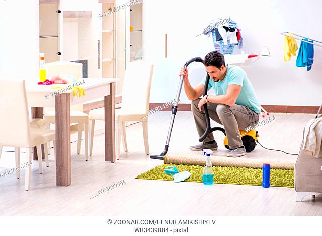 Young man husband doing vacuuming at home