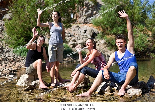 Teenagers waving from rocky river