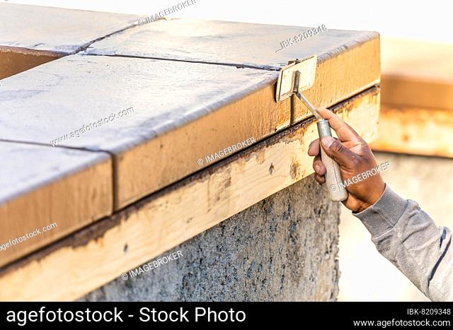 Construction worker using hand groover on wet cement forming coping around new pool