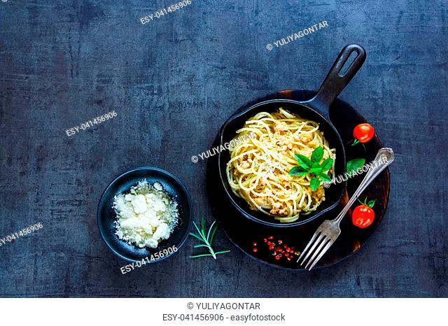 Italian food concept. Pasta with creamy crab sauce in black cast iron pan on vintage stone background. Top view. Copy space