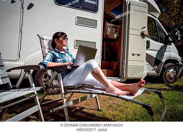 Woman looking at the laptop near the camping . Caravan car Vacation. Family vacation travel, holiday trip in motorhome RV