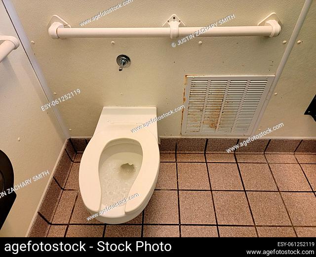 toilet and rusty heater vent in bathroom or restroom stall