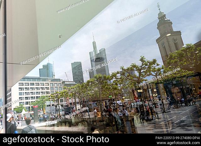 13 May 2022, Hessen, Frankfurt/Main: Buildings on the Hauptwache are reflected in the window of a store. Hessian city centers are to be redesigned to counteract...