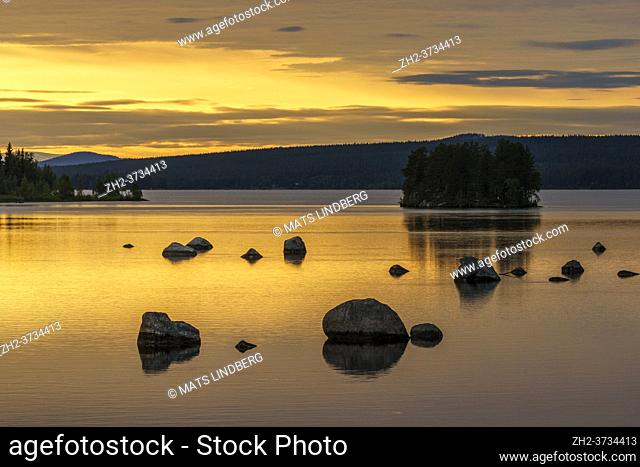 Sunset at Stora luleälven with nice color in the sky and reflection in the water, some rocks in the water, Jokkmokk, Stora luleälven, Swedish Lapland, Sweden