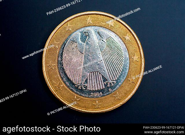 SYMBOL - 22 June 2023, Berlin: An old 1-euro coin lies on the table. It bears the traditional symbol of German sovereignty, the eagle