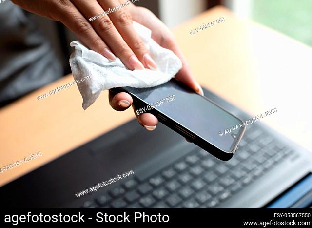 Work from home safe, cleaning and disinfecting smartphone and laptop computer with wet wipes