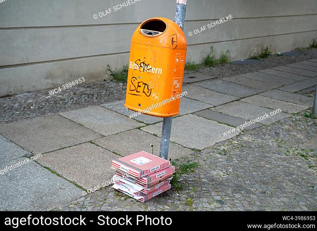 Berlin, Germany, Europe - Empty and discarded pizza cartons lie on the ground next to a dustbin in Mitte district