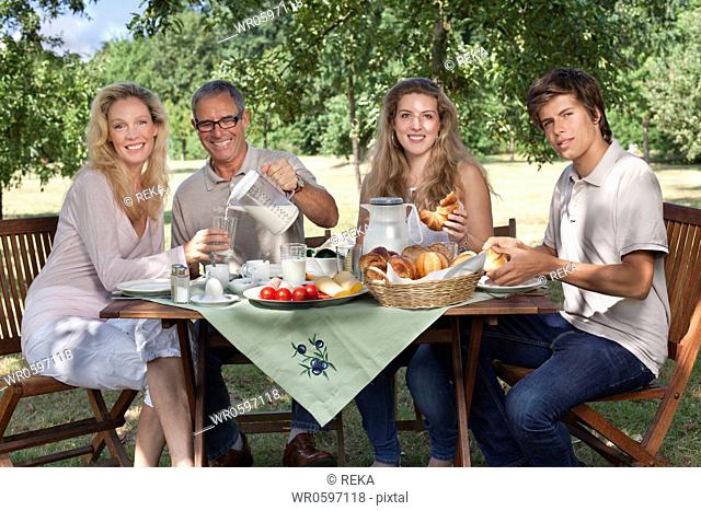 Family of four having breakfast at garden table
