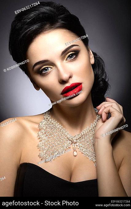 Beautiful woman with evening make-up, red lips and evening hairstyle. Beauty face. Picture taken in the studio on a gray background