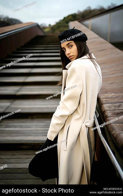 Young woman looking over shoulder while standing on staircase