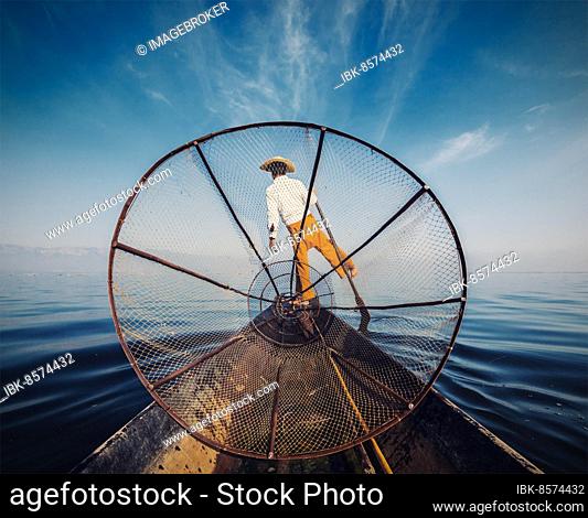 Myanmar travel attraction, Traditional Burmese fisherman with fishing net at Inle lake in Myanmar, view from boat. Vintage filtered retro effect image