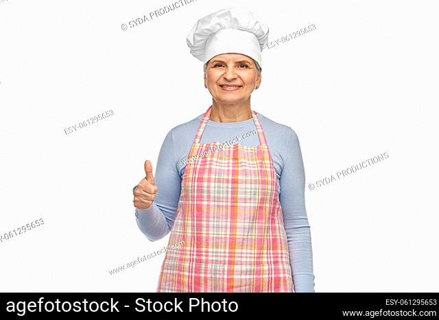 smiling senior woman or chef in toque in apron