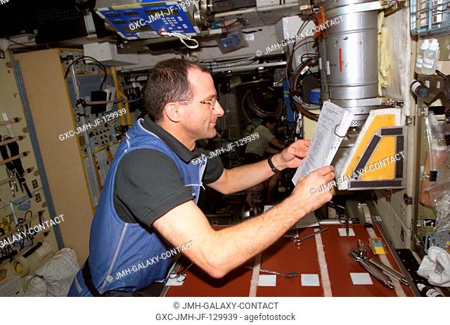 Astronaut Donald R. Pettit, Expedition Six NASA ISS science officer, looks over a procedures checklist in the Zvezda Service Module (SM) on the International...
