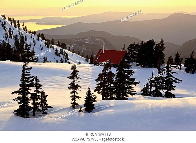 The sun sets on Mt. Steele cabin in Tetrahedron Provincial park on the Sunshine Coast with the Strait of Georgia and Vancouver Island as backdrop
