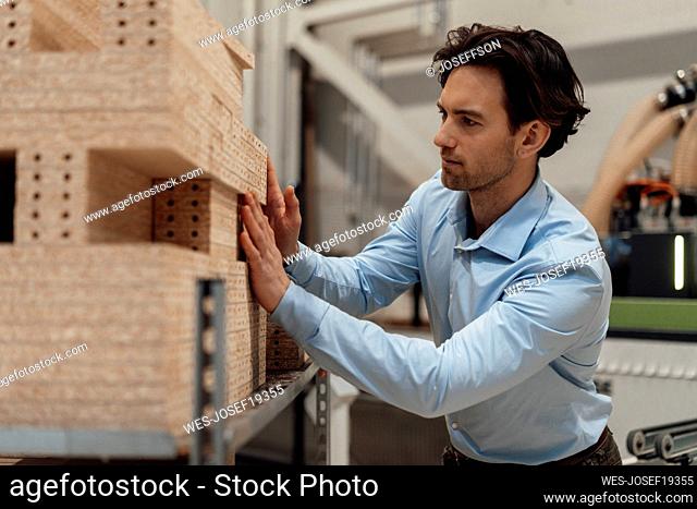 Businessman stacking wood on rack in industry