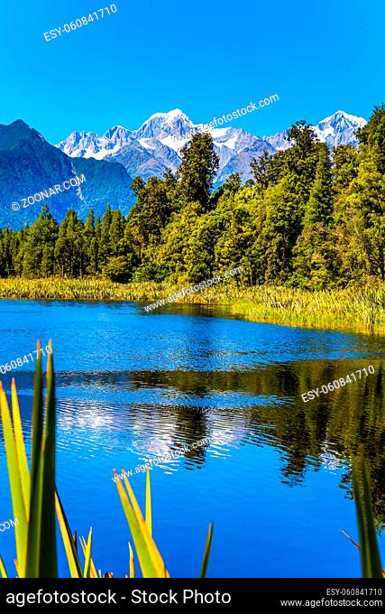 Lake Matheson is glacial lake. Mountain peaks covered with snow. Glacial lake surrounded by forests. South Island of New Zealand