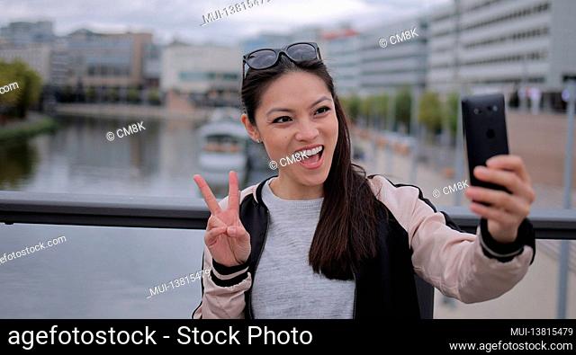 Young Asian woman takes a selfie in an urban area - people photography