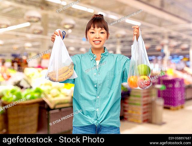 woman with fruits in reusable and plastic bags