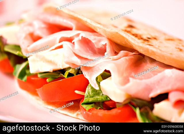 Traditional Italian piadina with ham, cheese, tomato and salad
