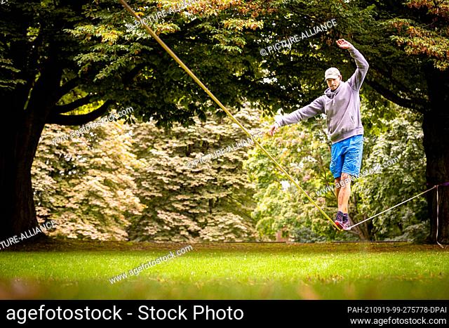 19 September 2021, Lower Saxony, Hanover: A man balances on a slackline in the Maschpark in cloudy weather. Photo: Moritz Frankenberg/dpa