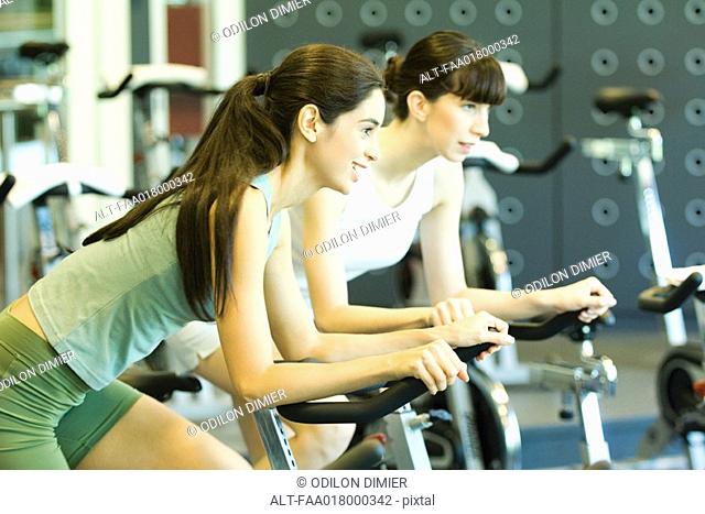 Two women riding exercise bikes