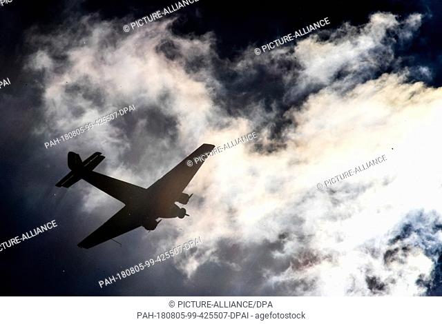 FILED - ILLUSTRATION - 22 May 2017, Germany, Cologne: A historical Junkers Ju 52 plane flies over Cologne against the light
