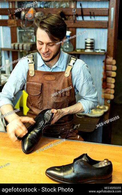 Male cobbler polishing shoe at workshop