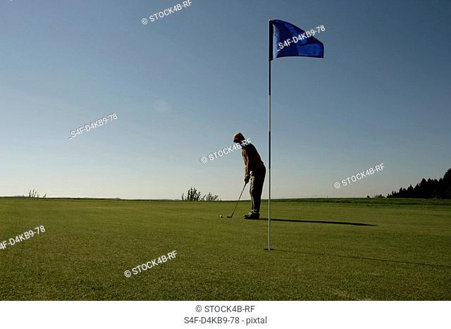 Man on golf course preparing to putt