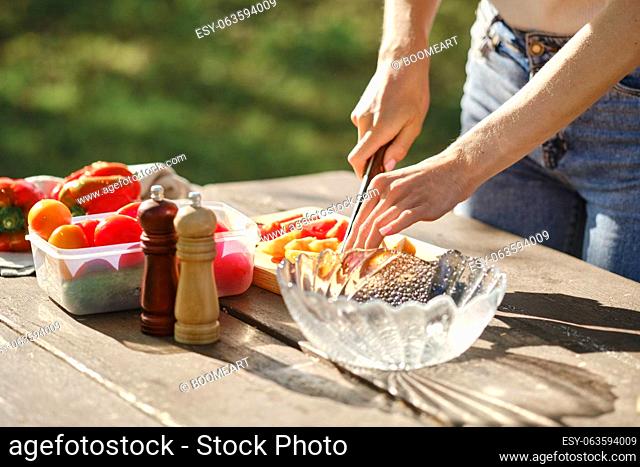 Closeup view of female hands cutting tomatoes for outdoor at picnic