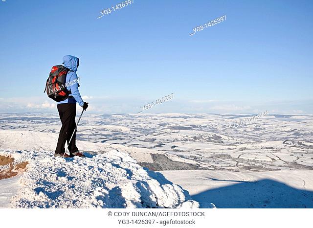 Female hiker in winter looks out from summit of Corn Du, Brecon Beacons national park, Wales