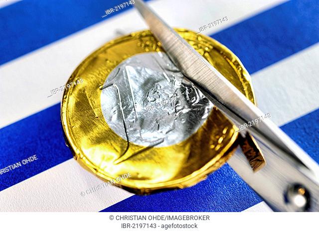 Scissors cutting a euro coin, symbolic image for debt cuts for Greece