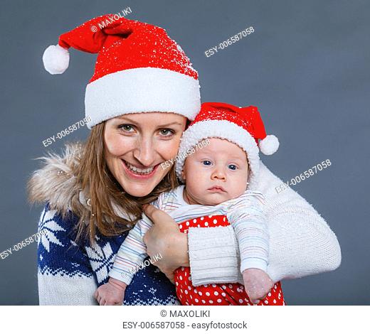 Christmas theme - Portrait of happy mother with babyboy in Santa's hat in studio
