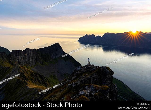 Tourist contemplating the fjord at dawn standing on top of Husfjellet mountain, Senja island, Troms county, Norway, Scandinavia, Europe