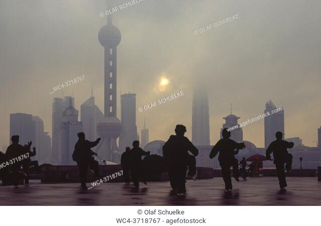 Shanghai, People's Republic of China, Asia - Early morning tai chi exercise with a view from The Bund across the Huangpu River of the central business district...