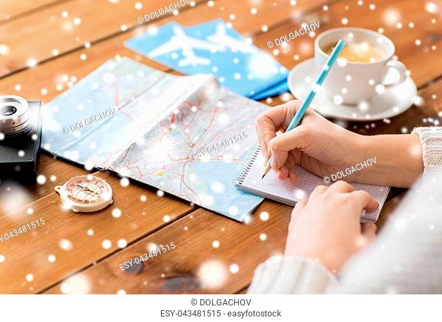 vacation, tourism, travel, winter holidays destination and people concept - close up of traveler hands with blank notepad and pencil