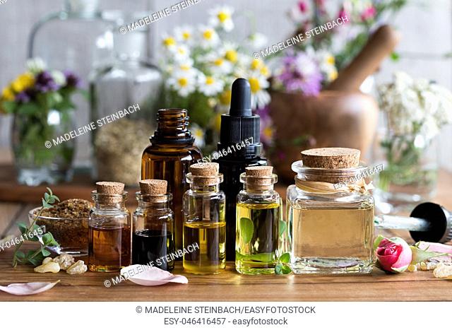 Selection of essential oils with various herbs and flowers in the background