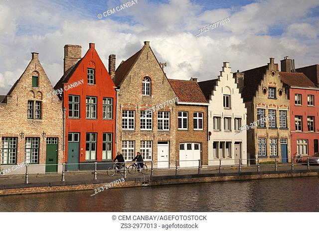 Cyclists in front of the the colorful traditional houses by the canal in the city centre, Bruges, West Flanders, Belgium, Europe