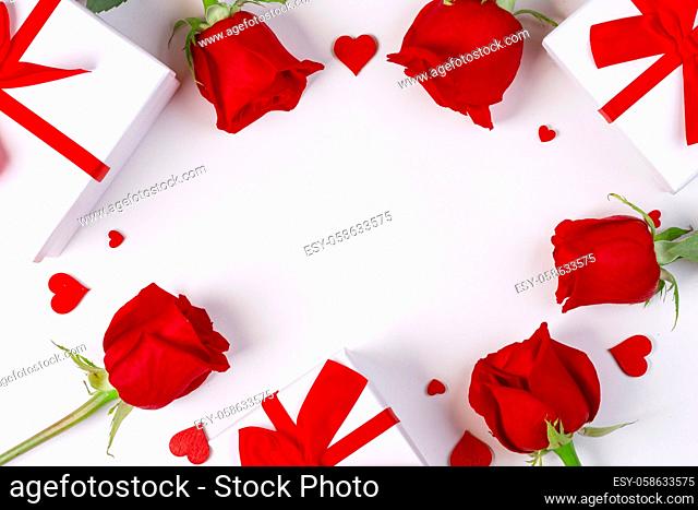 Red rose flowers gifts and red hearts composition on white background top view with copy space. Valentine's day, birthday, wedding, Mother's day concept