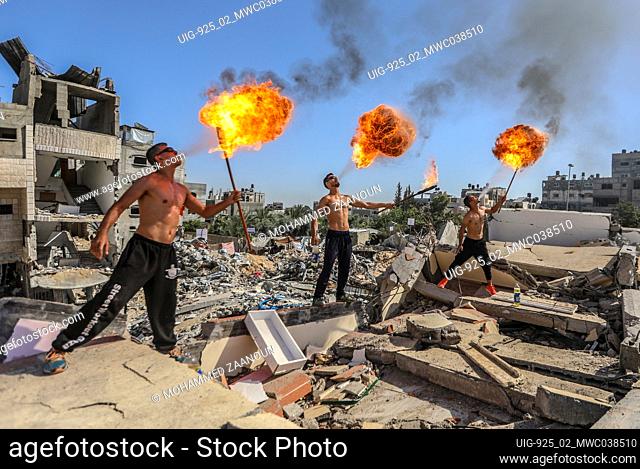Beit Lahia, northern Gaza Strip. 26th May 2021. Palestinian youth perform fire breathing at the ruins of a building destroyed in recent Israeli air strikes