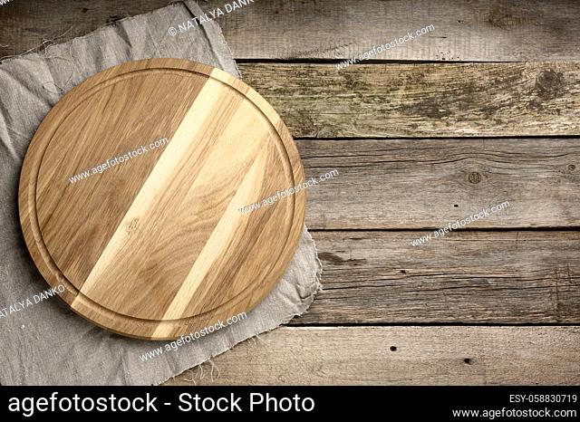 empty round wooden cutting kitchen board on wooden background, pizza board, copy space