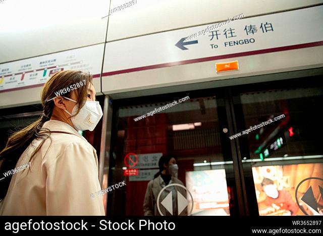 Wearing a mask of the young woman stood on the subway platform