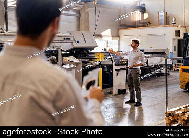 Businessman discussing with colleague while standing at factory