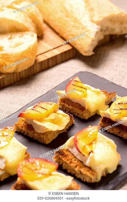 canapes, appetizer with grilled brie and nectarine plated on a slate dish